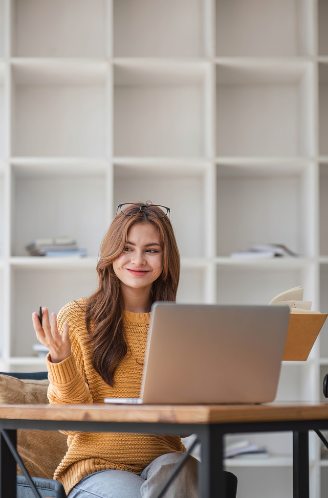 Młoda kobieta siedzi za laptopem i uczy się online, skupiona na nauce języków.