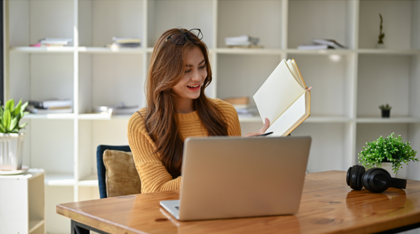Młoda kobieta siedzi za laptopem i uczy się online, skupiona na nauce języków.